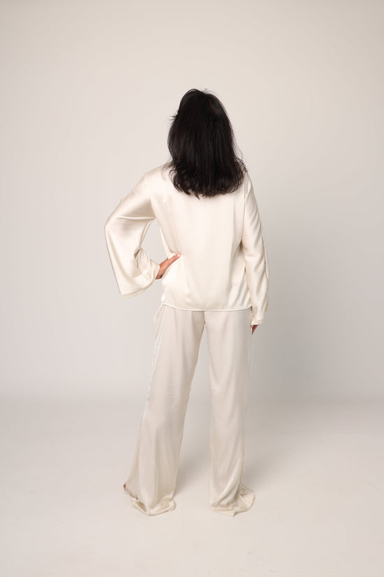 Person wearing a white outfit standing against a plain background