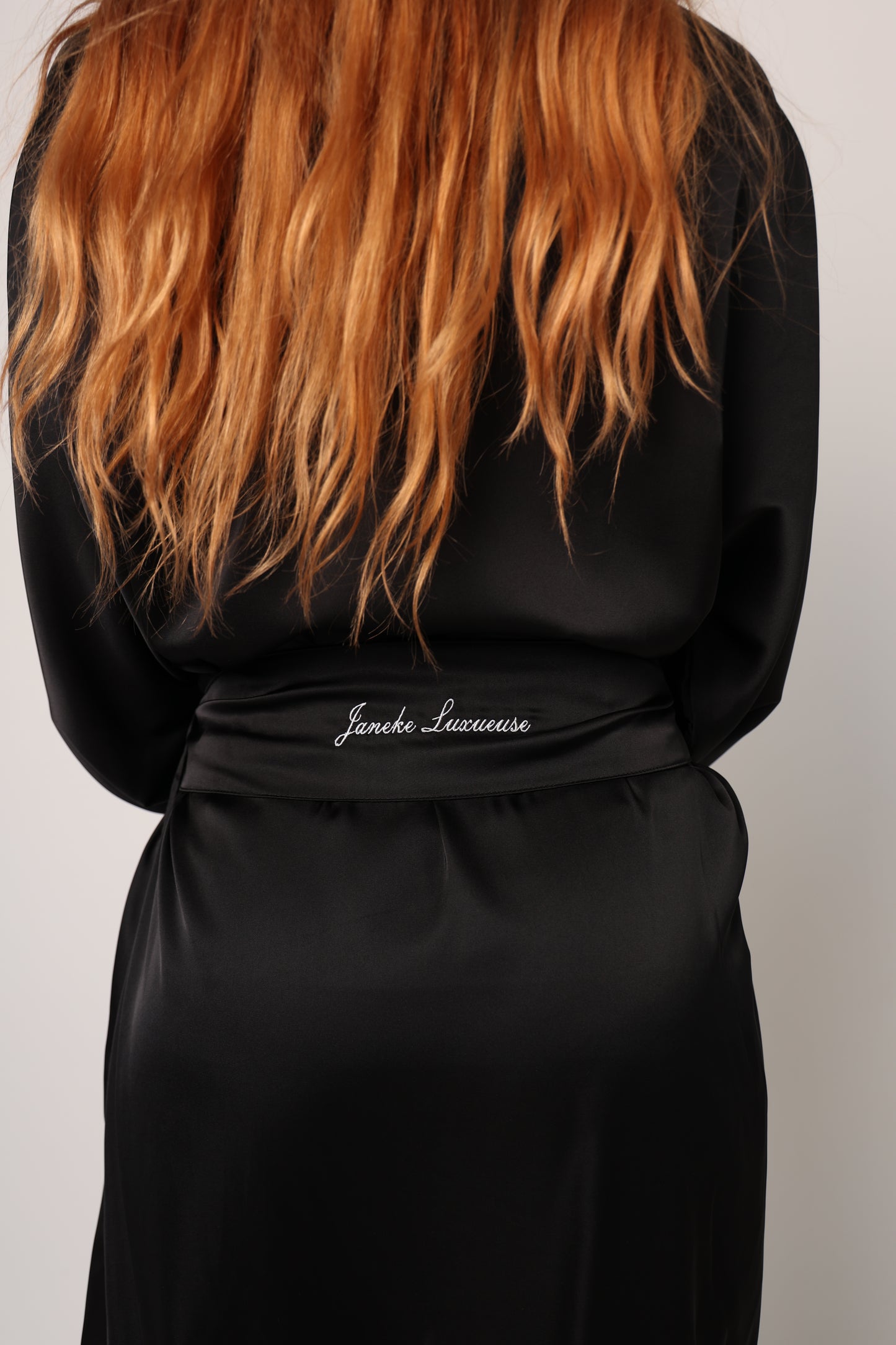 Black hair extension with brown roots on a gray background
