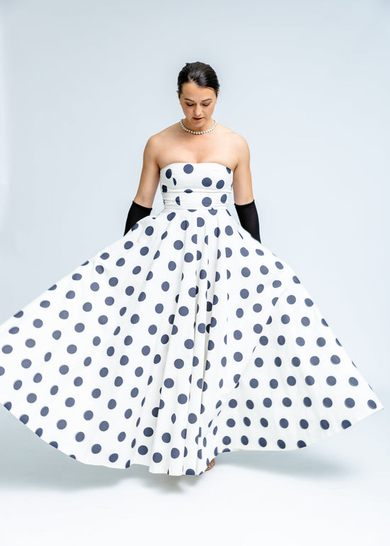 Woman wearing a strapless polka dot dress on a plain background