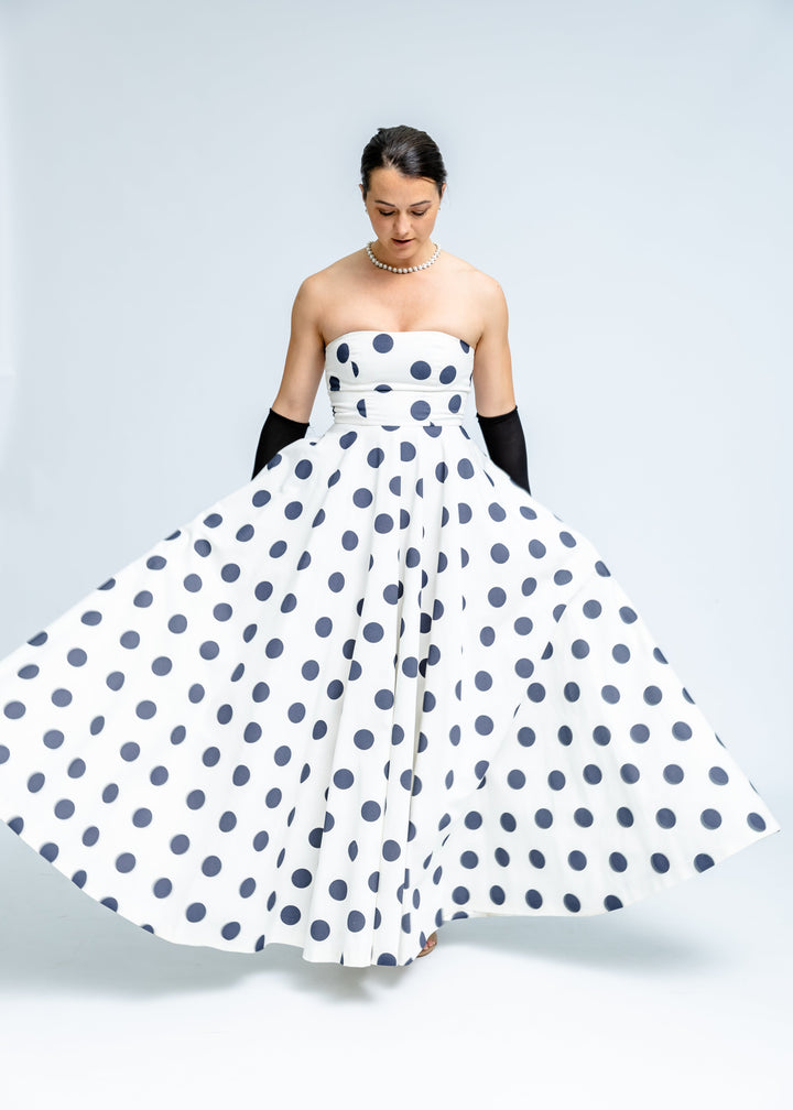 Woman wearing a strapless polka dot dress on a plain background