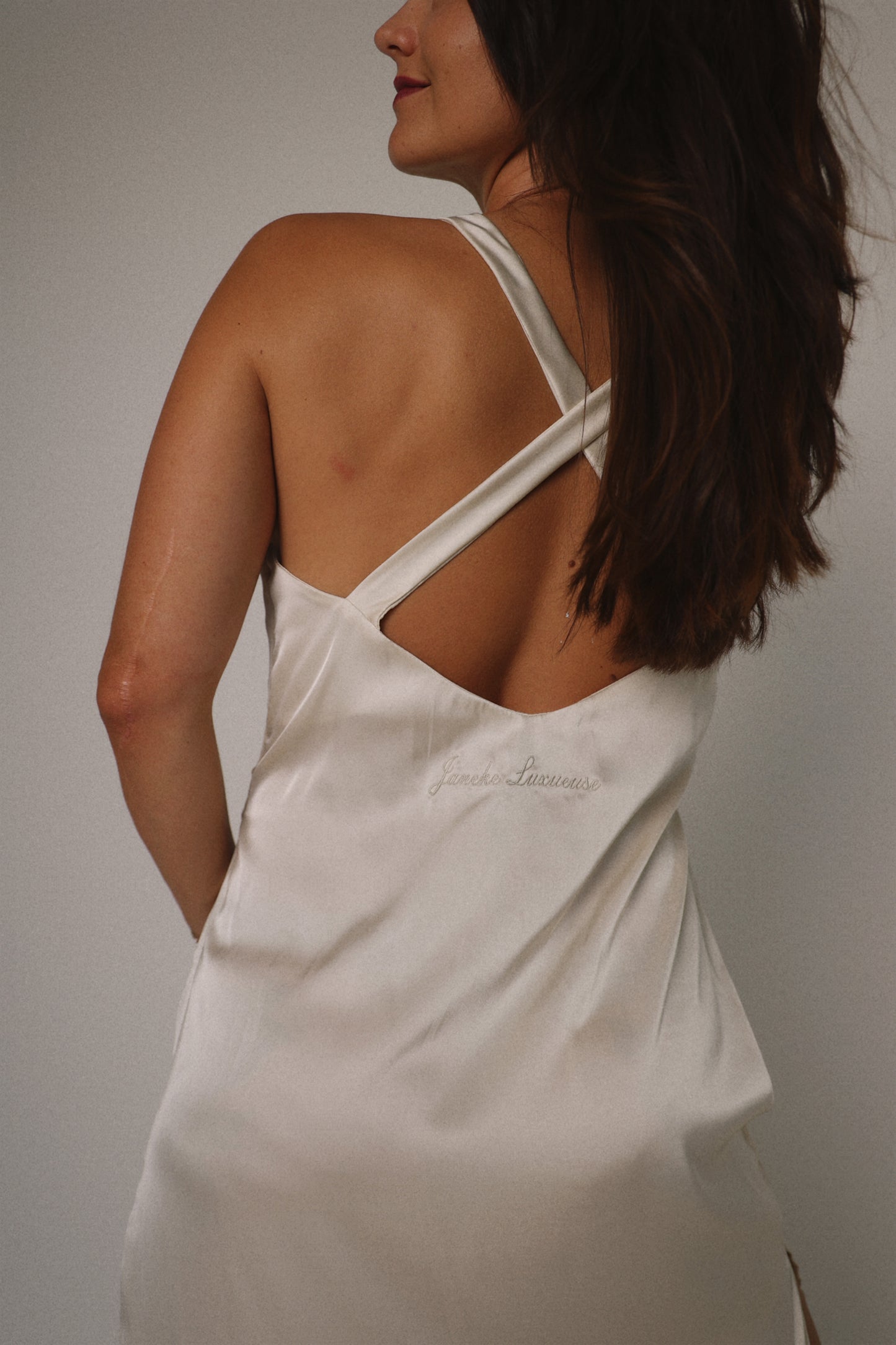 Woman wearing a white tank top against a neutral background