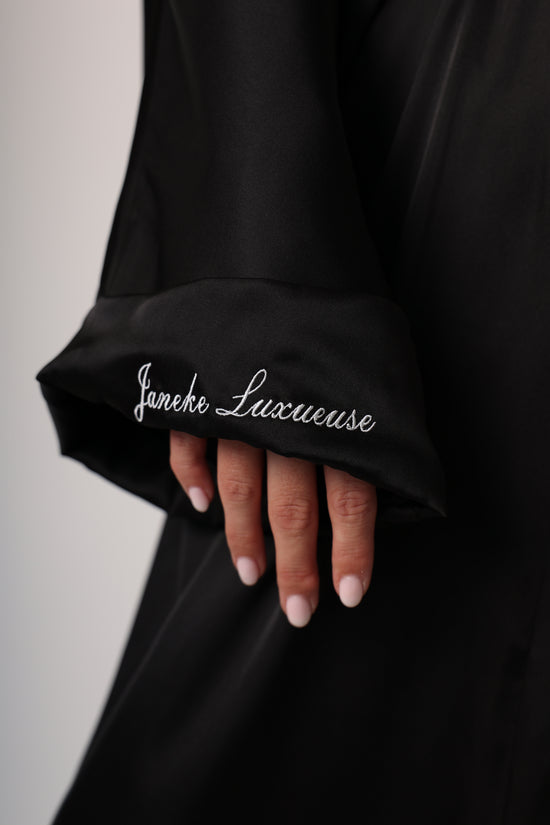 Hand holding a black satin pillowcase with 'Janeke Luxe' branding.