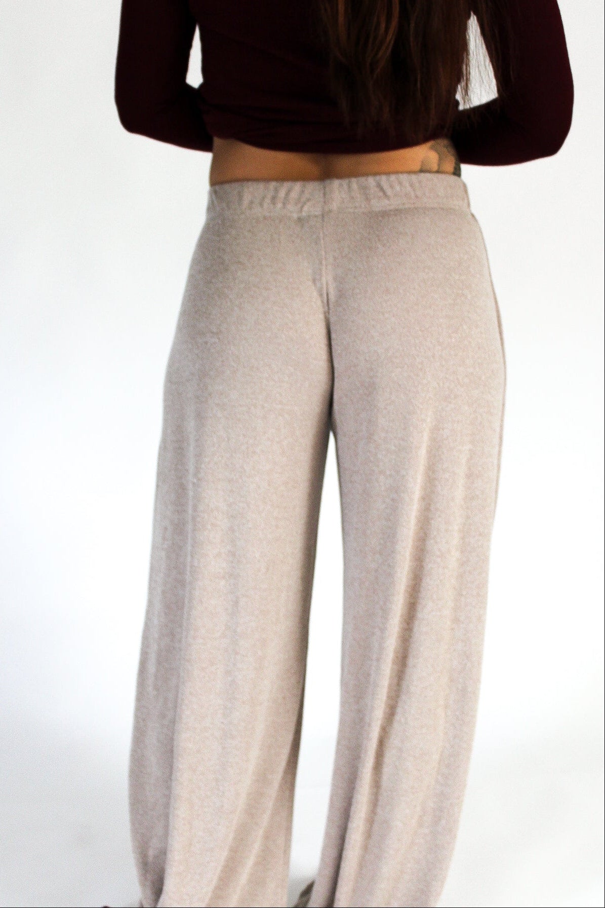 Person wearing beige pants and a dark top on a white background