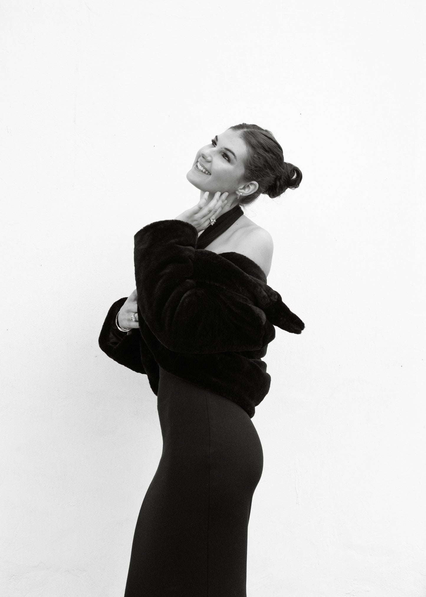 Black and white portrait of a woman wearing a black coat against a white background
