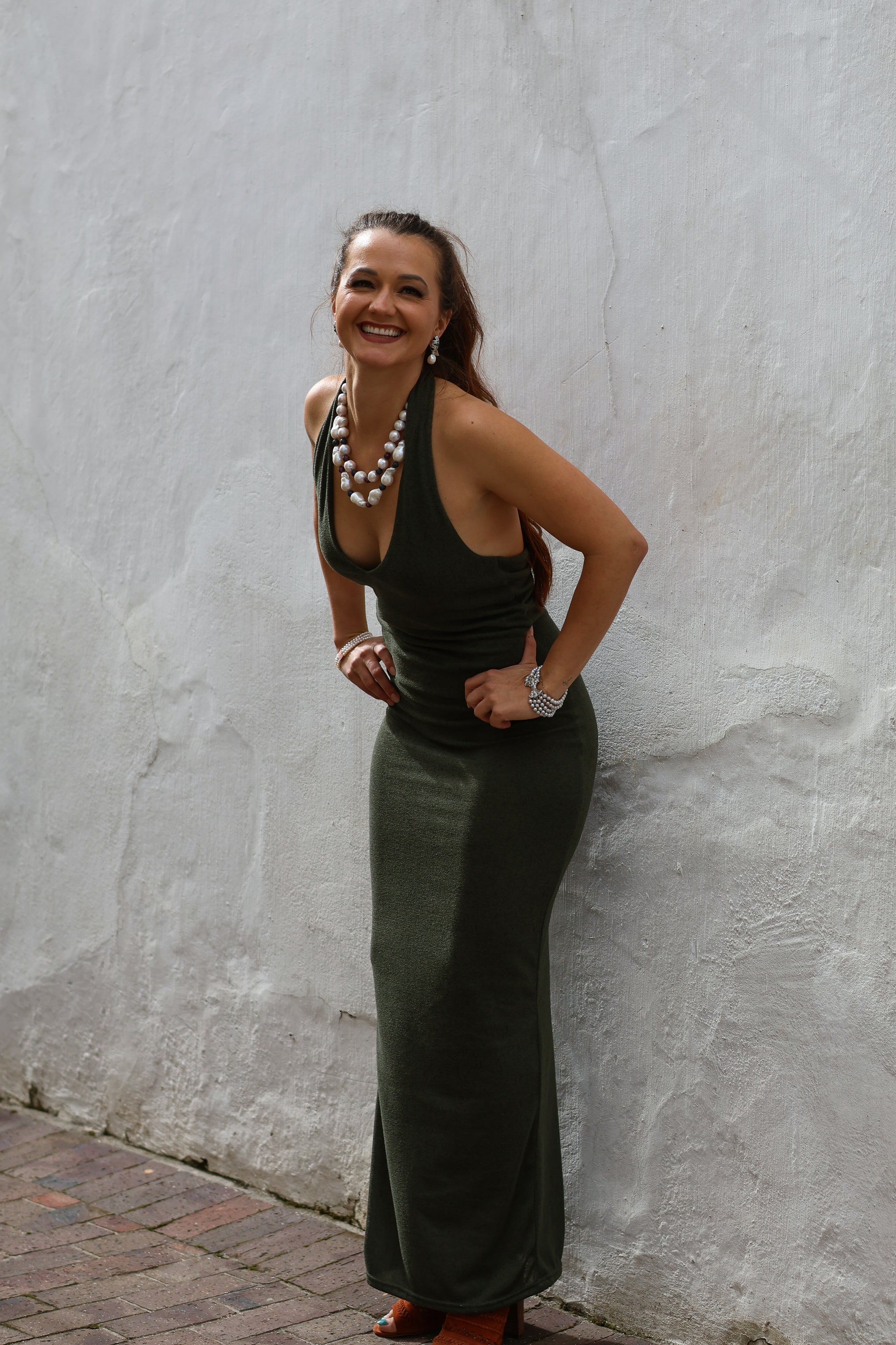 Woman in a green dress standing against a textured wall.