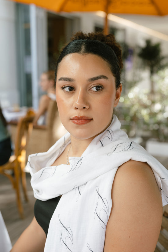 Woman wearing a white patterned scarf in an outdoor setting