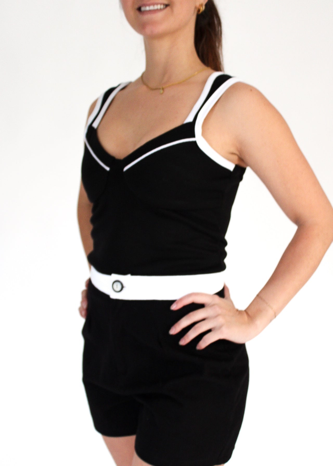 Woman wearing a black outfit with white trim on a plain background