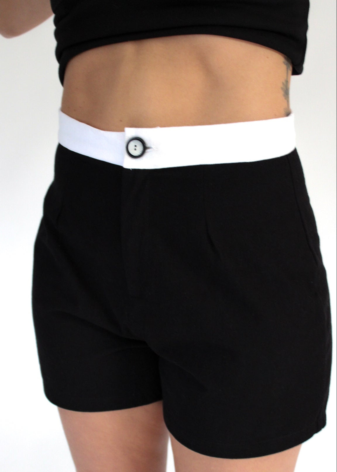 Black shorts with a white waistband on a plain background