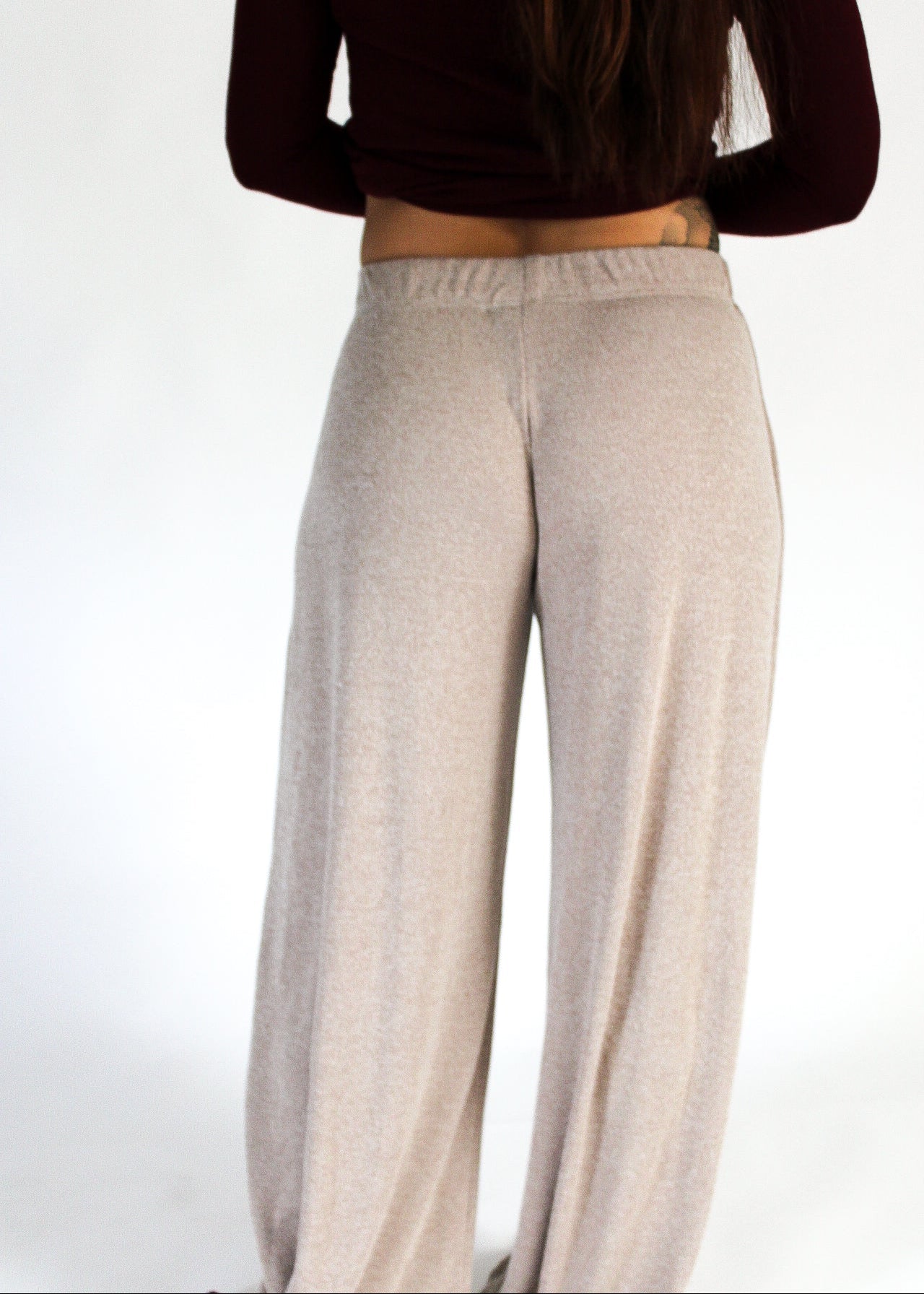 Person wearing beige pants and a dark top on a white background