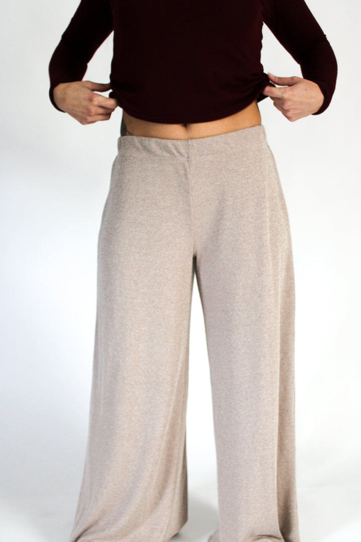 Person wearing a burgundy top and beige wide-leg pants on a white background