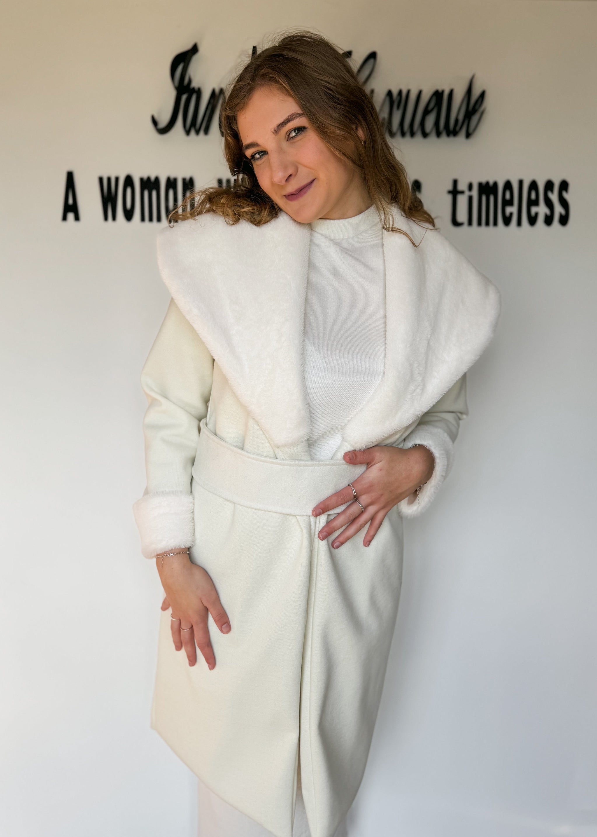 Woman wearing a white coat with text on a wall behind her