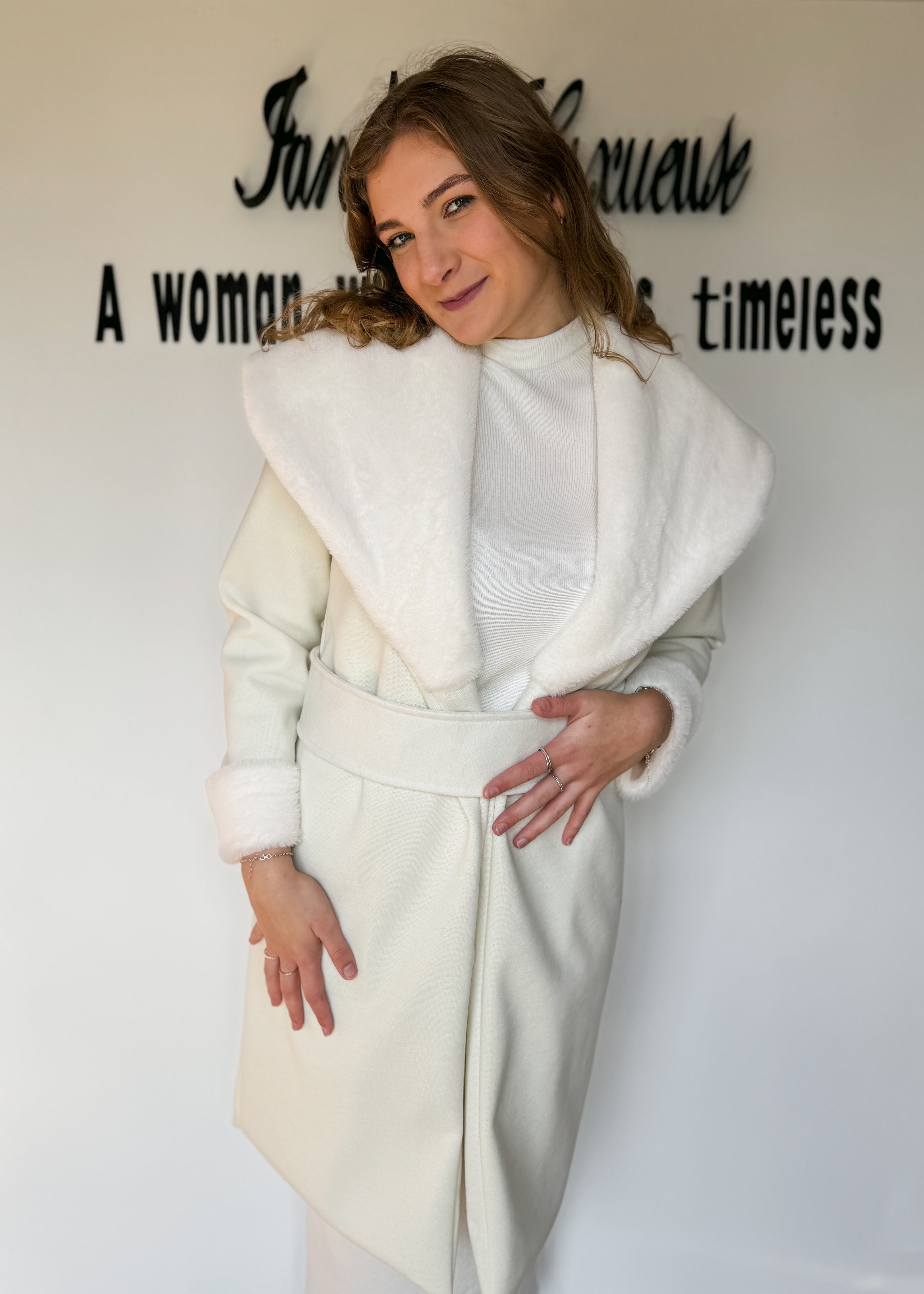 Woman wearing a white coat with text on a wall behind her