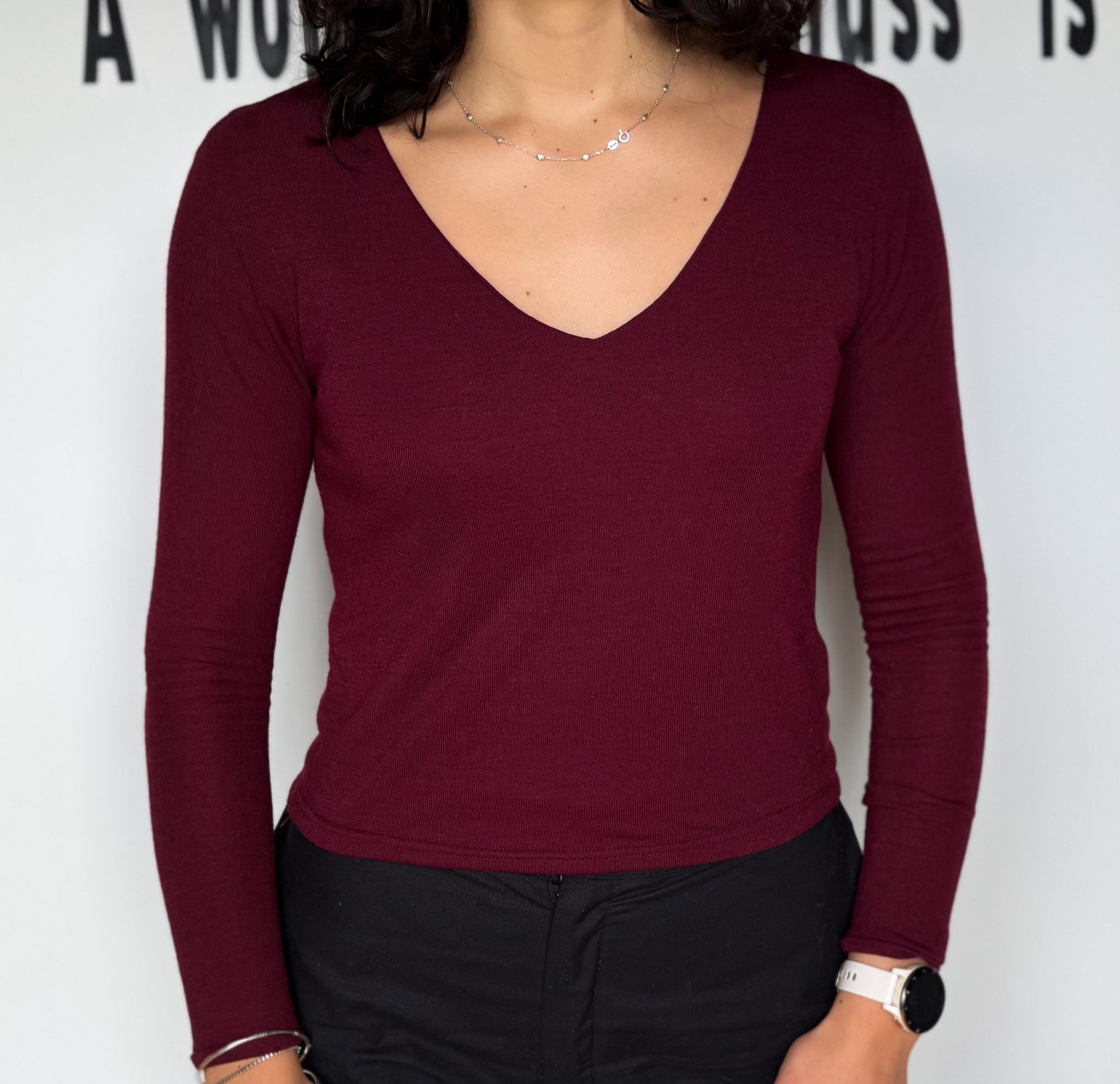 Person wearing a burgundy long-sleeve top against a white background