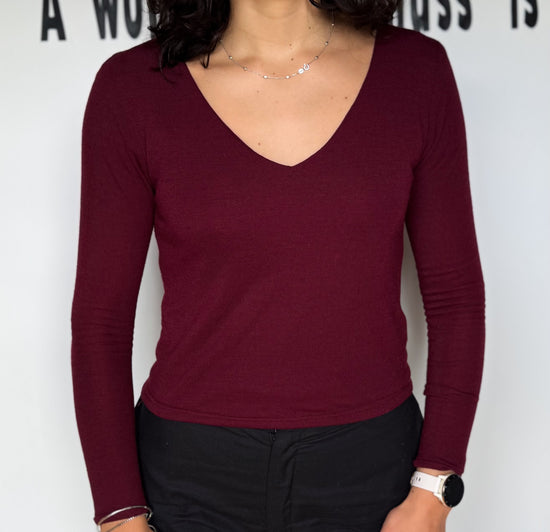 Person wearing a burgundy long-sleeve top against a white background