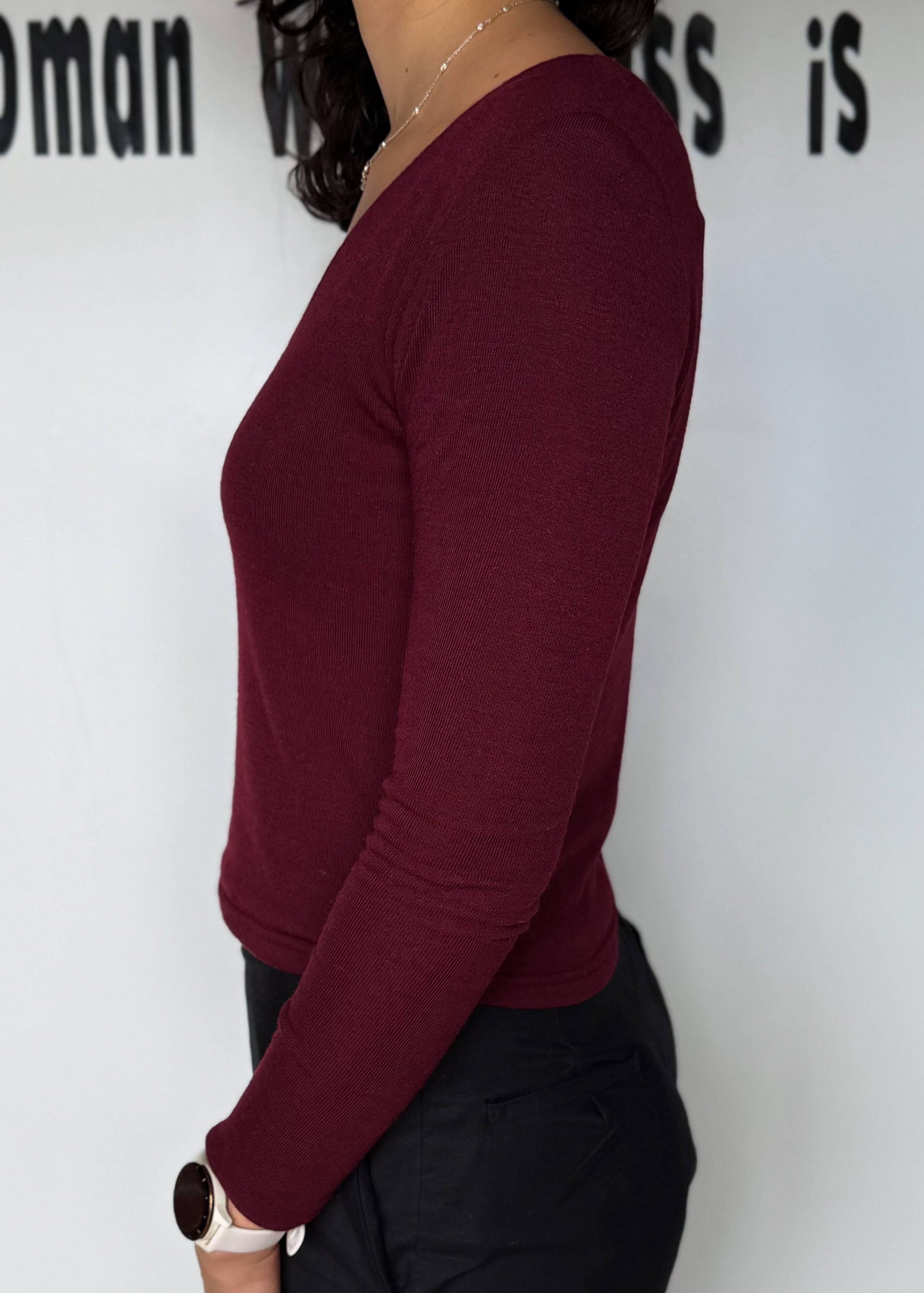 Person wearing a burgundy long-sleeve top against a white background with text.