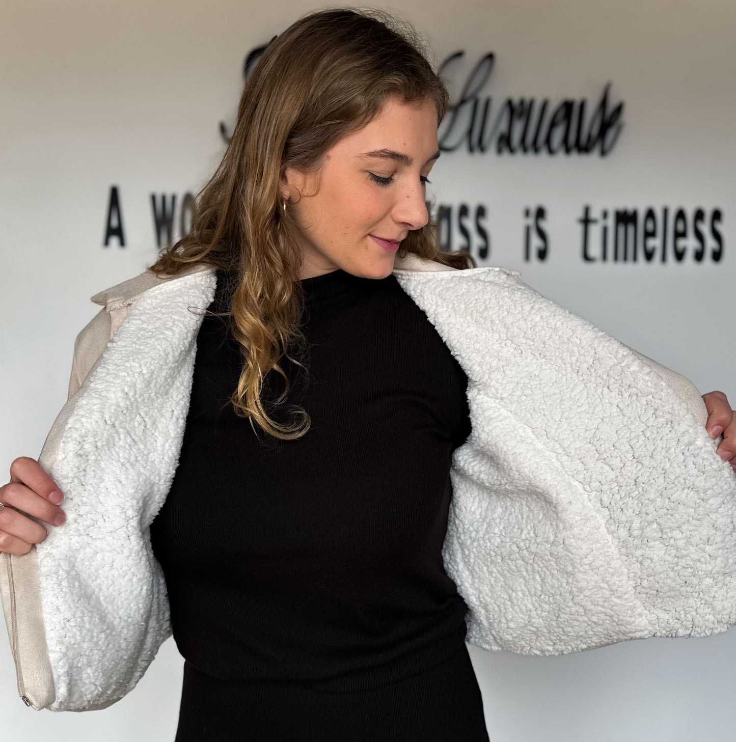 Woman holding a white textured jacket against a plain background