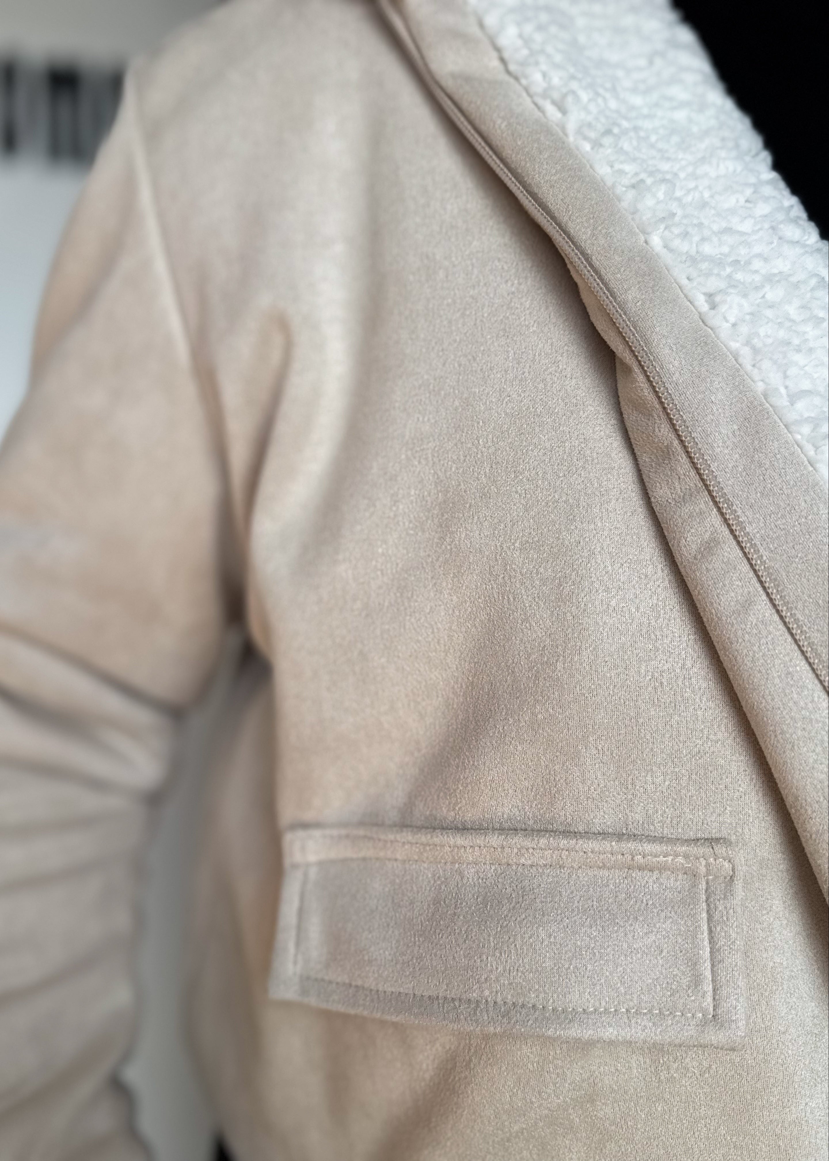 Close-up of a beige jacket with a pocket detail.