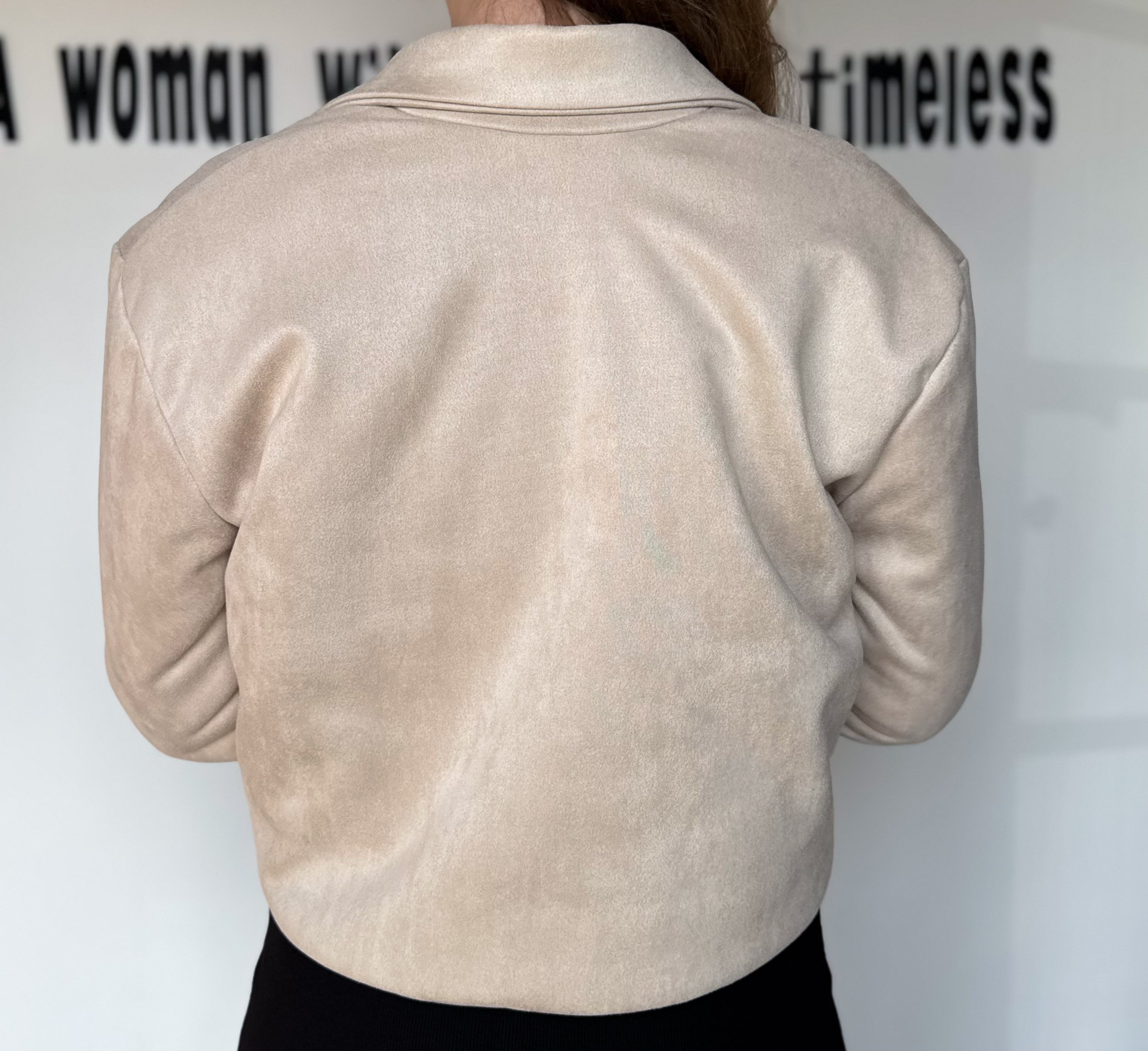 Beige jacket worn by a person with a white background and text.
