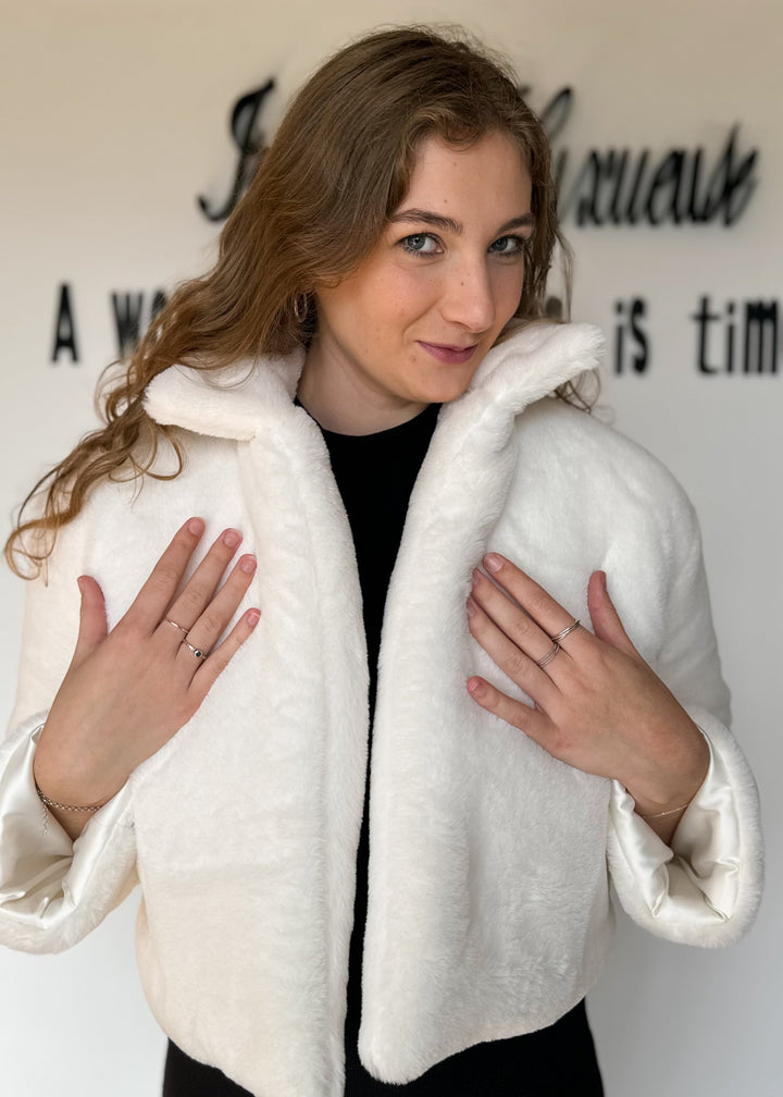 Woman wearing a white textured jacket against a neutral background