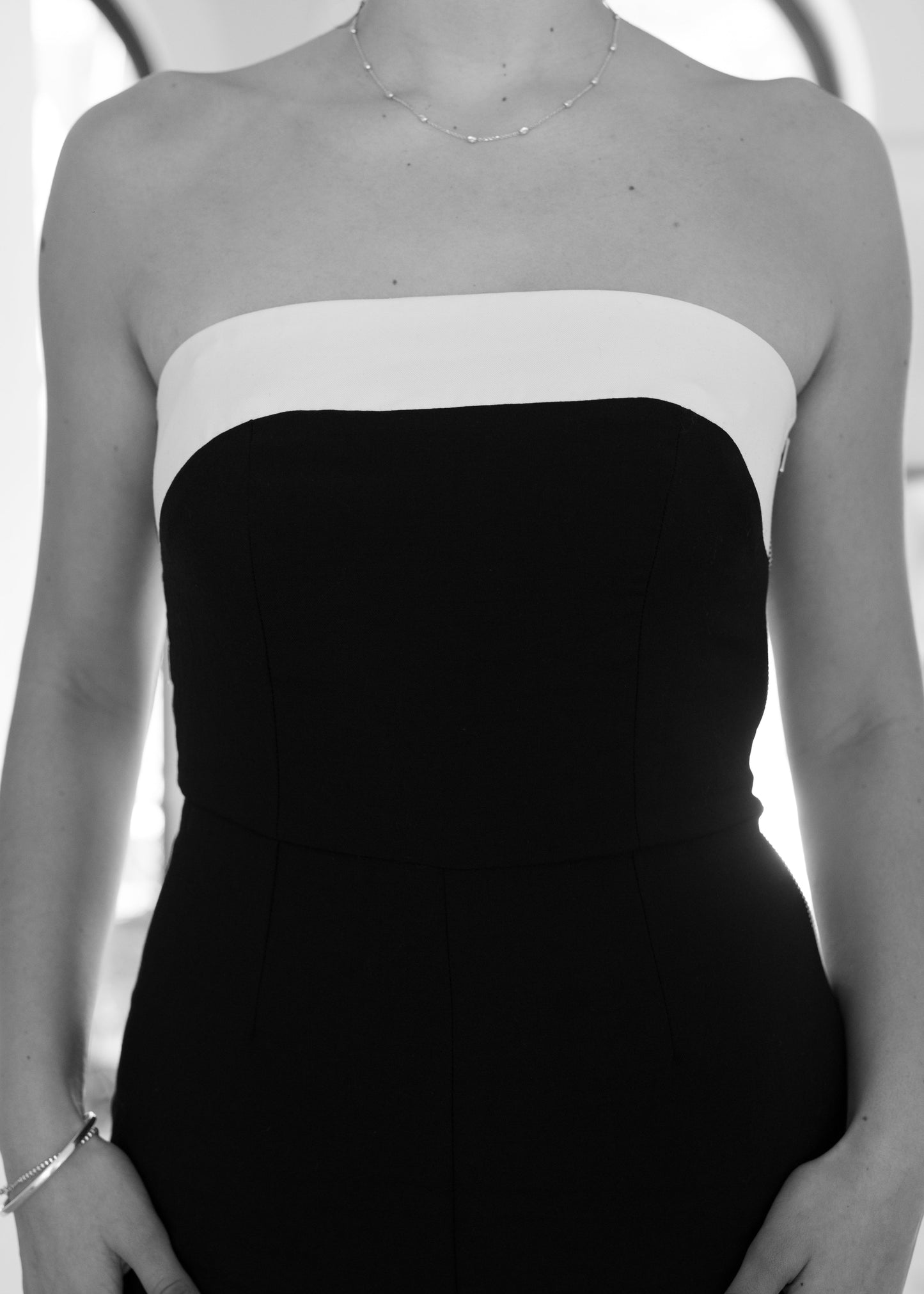 Black and white strapless dress worn by a person on a plain background