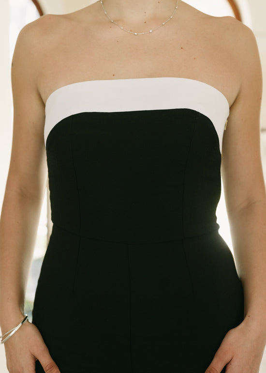 Black and white strapless dress worn by a person with a neutral background