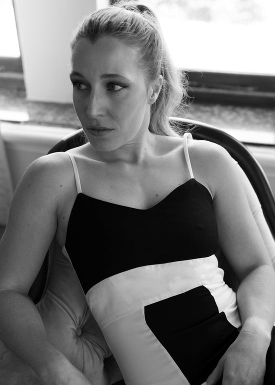 Black and white photo of a woman sitting inside a vehicle.