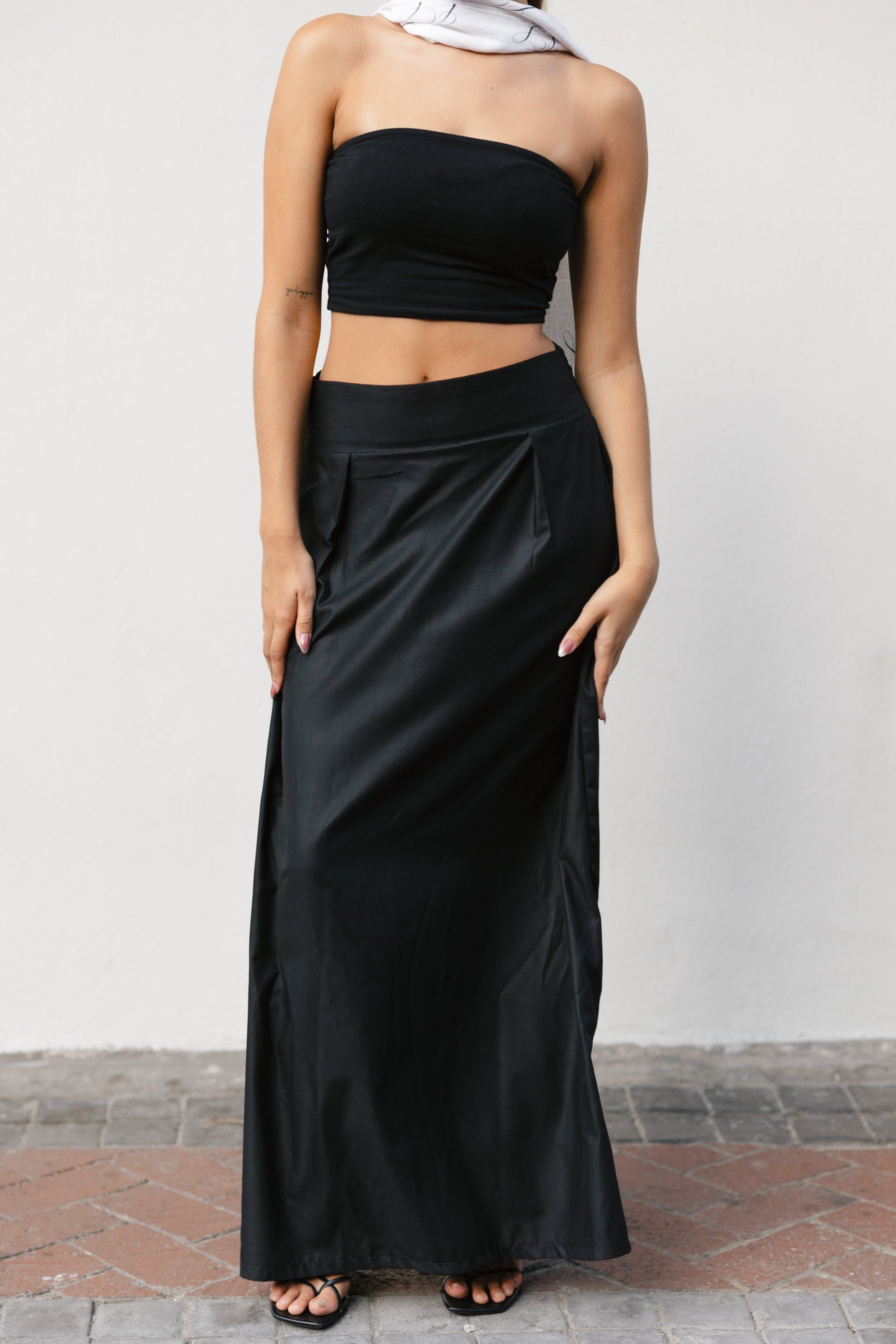 Woman wearing a black strapless top and long black skirt against a plain background